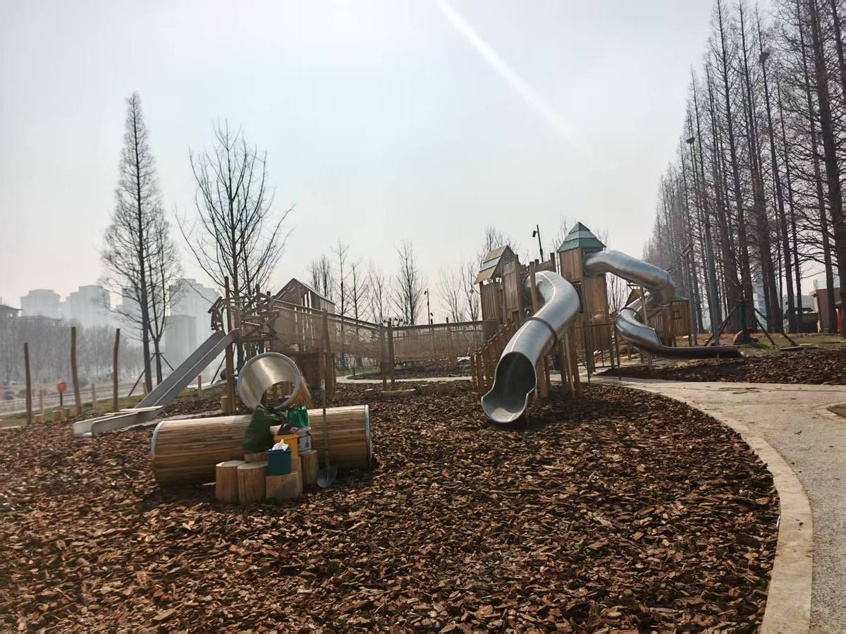 rope tube slide and open timber platforms inside a low age play zone with wood chip surfacing горка из веревочной трубы и открытые деревянные платформы внутри игровой зоны для детей младшего возраста с покрытием из древесной щепы